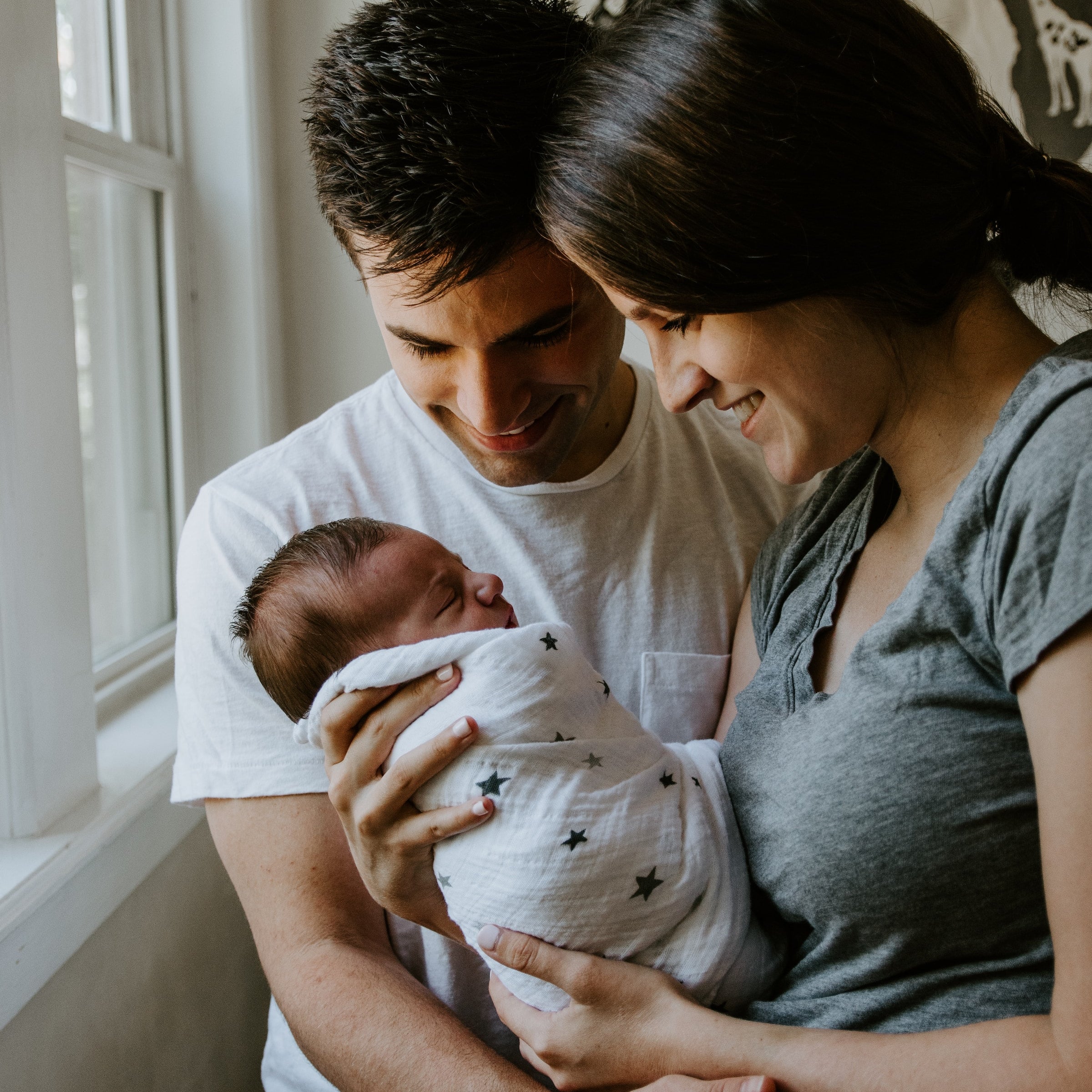 Parents hold a baby wrapped in atluxe soft, sustainable bamboo swaddle
