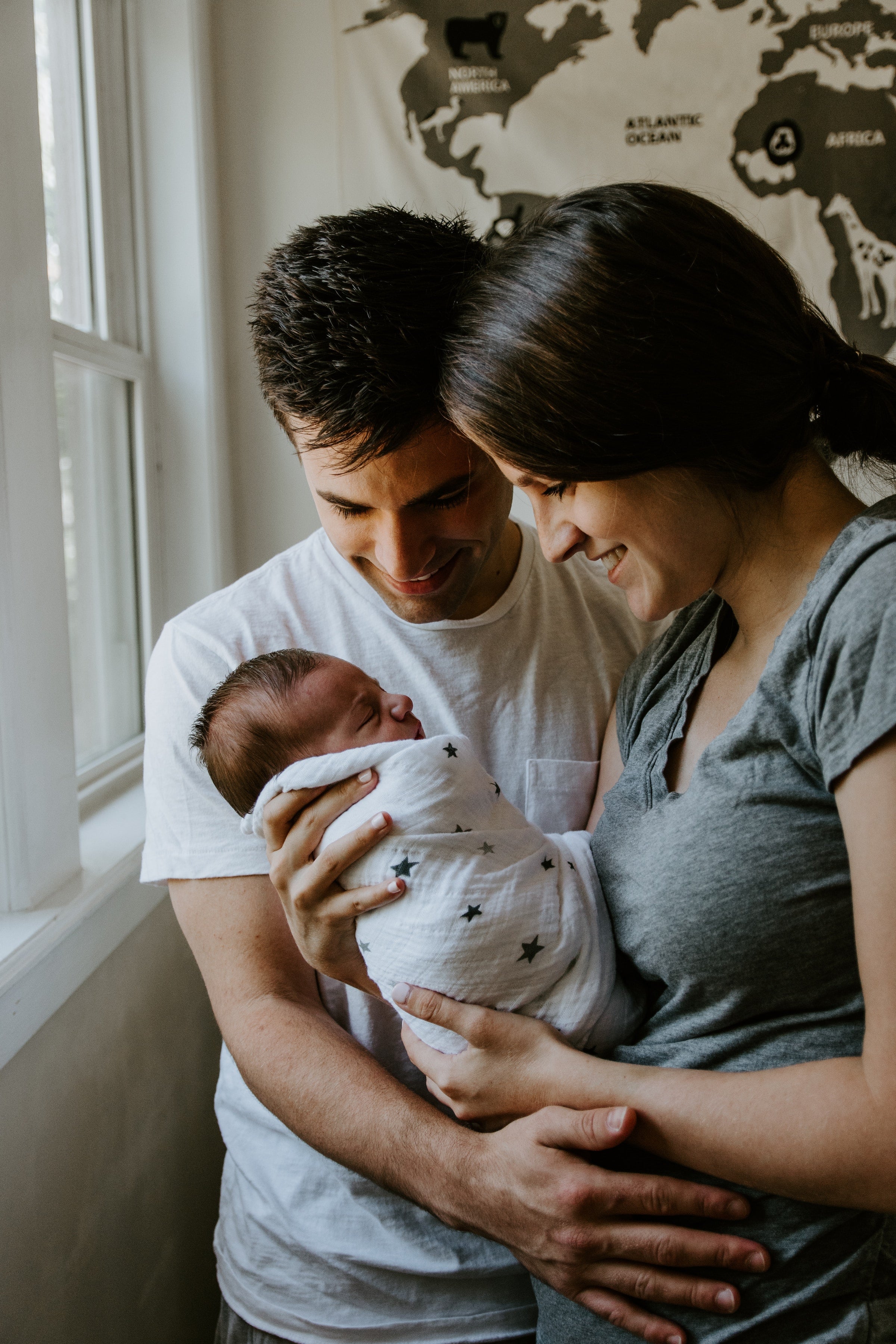 Parents hold a baby wrapped in atluxe soft, sustainable bamboo swaddle