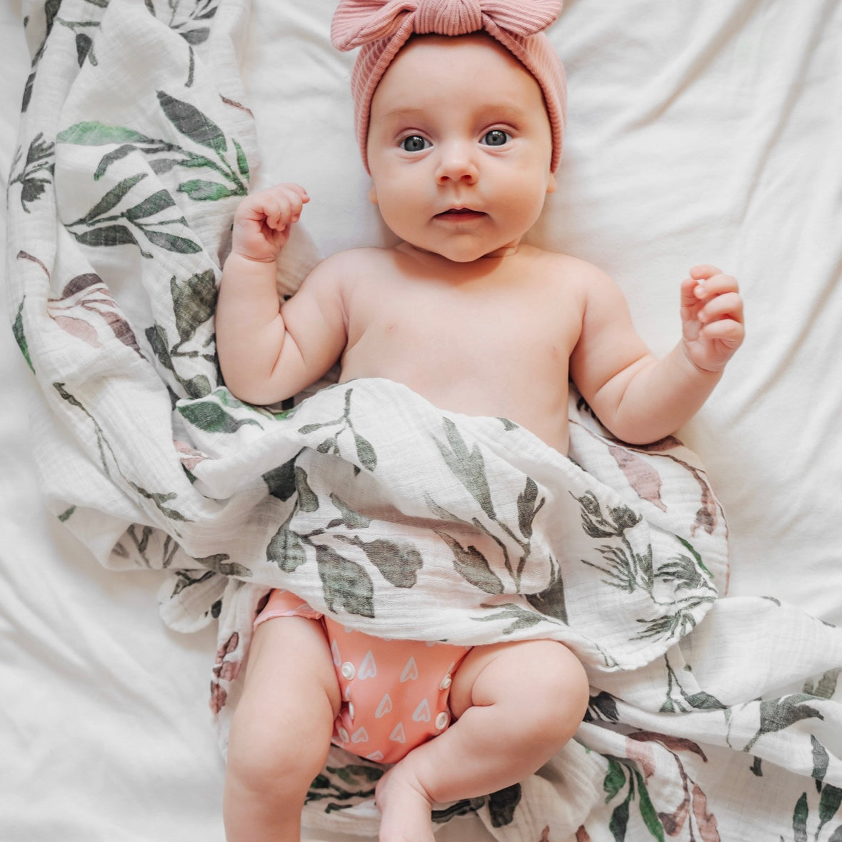 Baby about to be wrapped in atluxe bamboo swaddle